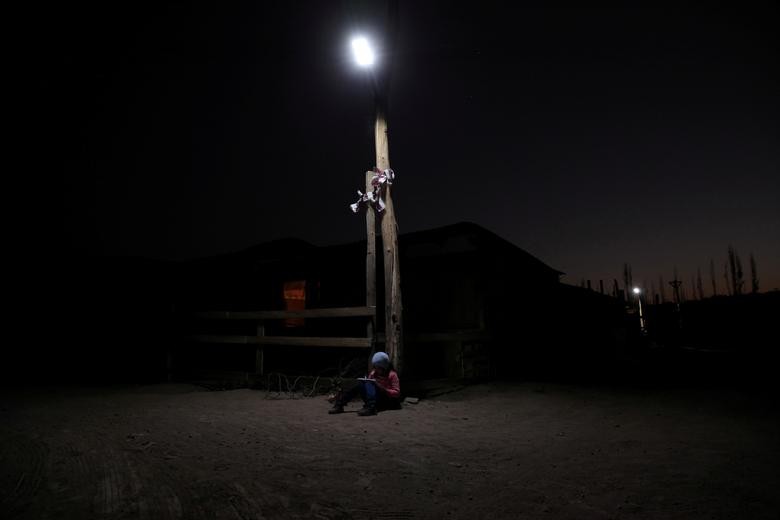 Violet sits under a solar lamp while she works on her drawing in the community "El sueno de todos" (Everybody's dream) an unauthorized settlement without potable water, drainage system and electricity, where people have moved in with their families after losing their jobs and income, during the coronavirus disease (COVID-19) outbreak, at Puente Alto area, on the outskirts of Santiago, Chile October 14. REUTERS/Ivan Alvarado